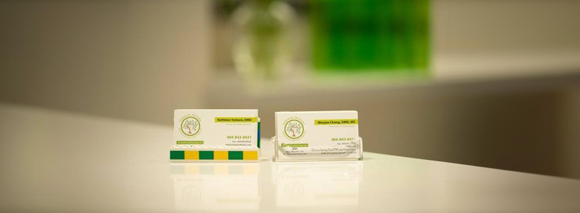 The image shows a group of people, possibly professionals given their attire and the setting that appears to be an office or professional environment. They are gathered around a table with a laptop on it, engaged in what seems to be a discussion or meeting.